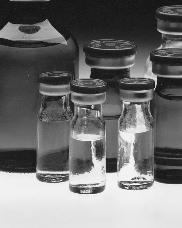 Real small glass medicine vials with rubber stoppers and metal seals (black-and-white photo).