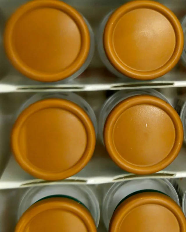 Rows of real medicine vials seen from above, with brown flip-off caps.